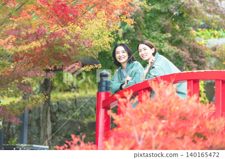 一位身穿浴衣的中年婦女正在欣賞秋葉。 140165472