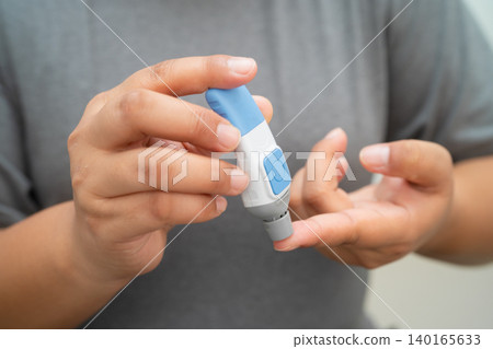 Asian woman self testing to check blood sugar level diabetes by digital lancet on finger at home. Asian woman self testing to check blood sugar level diabetes by digital lancet on finger at home. 140165633
