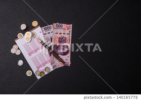 Lottery ticket, Mexican banknotes, and a pen, chance to win big, gambling. Lottery ticket Lottery ticket, Mexican banknotes, and a pen, chance to win big, gambling. Lottery ticket 140165778