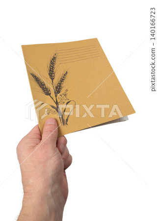 a hand shows the cover of a closed soviet notebook with a pattern of wheat ears a hand shows the cover of a closed soviet notebook with a pattern of wheat ears 140166723