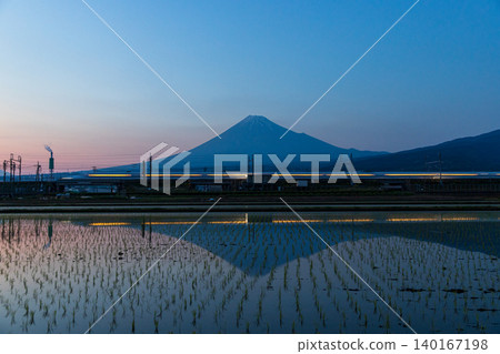 Mount Fuji reflected in the rice paddies at dusk after the rice planting is finished. 140167198