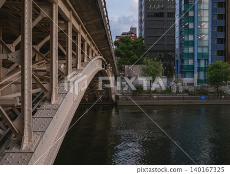 A historic, retro steel arch bridge and modern buildings reflected in the water. A historic, retro steel arch bridge and modern buildings reflected in the water. 140167325