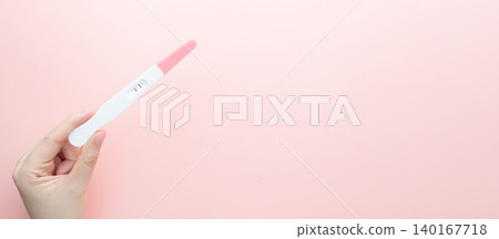 Pregnant woman holding a positive urine pregnancy test on pink background. Pregnancy test kit measure hCG levels in urine. Pregnant woman holding a positive urine pregnancy test on pink background. Pregnancy test kit measure hCG levels in urine. 140167718