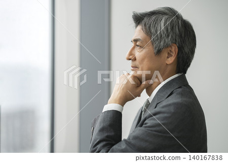 A senior businessman looking out the window (profile view) A senior businessman looking out the window (profile view) 140167838