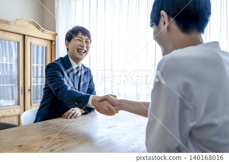 A sales representative and a young man shake hands after the contract is finalized. A sales representative and a young man shake hands after the contract is finalized. 140168016