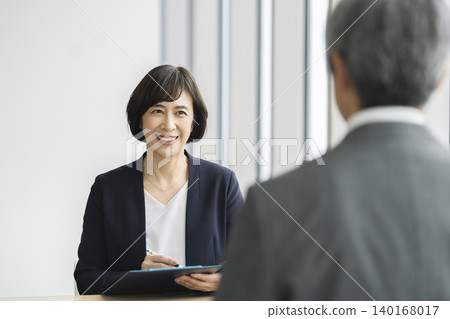 Interview/Meeting Image: A businesswoman speaking face-to-face with a senior man. 140168017
