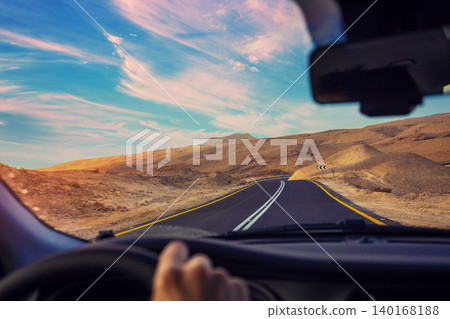 Driving a car on a mountain road. Desert landscape. Journey by car. View from the car of a mountain landscape in the evening. Israel Driving a car on a mountain road. Desert landscape. Journey by car. View from the car of a mountain landscape in the evening. Israel 140168188