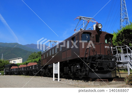 一列由 EF15-198 號機車牽引的貨運列車(保存完好的車輛)靜靜地停在那裡,被南阿爾卑斯山脈的山脈所守護著。 一列由 EF15-198 號機車牽引的貨運列車(保存完好的車輛)靜靜地停在那裡,被南阿爾卑斯山脈的山脈所守護著。 140168807
