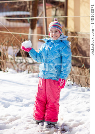 Smiling child colorful winter clothes standing on snow with trees and houses in sunny background Smiling child colorful winter clothes standing on snow with trees and houses in sunny background 140168871