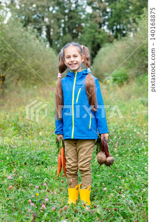 Smiling girl standing orchard holding carrots beets, wearing jacket during autumn harvest outdoors Smiling girl standing orchard holding carrots beets, wearing jacket during autumn harvest outdoors 140168875