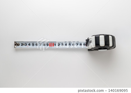 A photograph of a steel measuring tape taken from directly above against a white background. A photograph of a steel measuring tape taken from directly above against a white background. 140169095