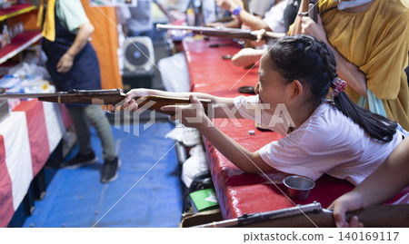 Children enjoying shooting games at a festival. Children enjoying shooting games at a festival. 140169117