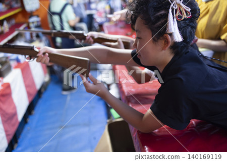 Children enjoying shooting games at a festival. Children enjoying shooting games at a festival. 140169119