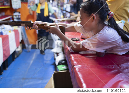 Children enjoying shooting games at a festival. Children enjoying shooting games at a festival. 140169121
