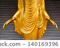 Close-up of Golden Buddha Statue Hands and Robe against Metal Shutter Background 140169396