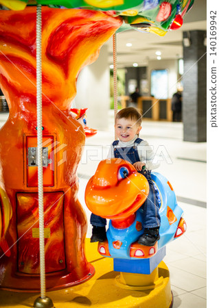 Little boy riding colorful carousel turtle shopping mall amusement area bright decorations Little boy riding colorful carousel turtle shopping mall amusement area bright decorations 140169942