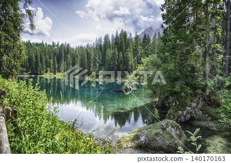 The emerald green Lake Carezza reflecting Latemar mountain, Dolomites, Italy The emerald green Lake Carezza reflecting Latemar mountain, Dolomites, Italy 140170163