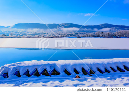 冬季山中湖的雪景，一排船隻被雪覆蓋，湖面完全凍結。 140170531