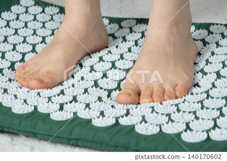 Woman Standing by Reflexology Acupressure Mat at Home 140170602