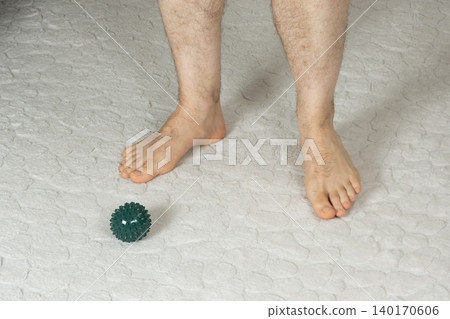Barefoot Man Standing Near Massage Ball on a Carpet 140170606