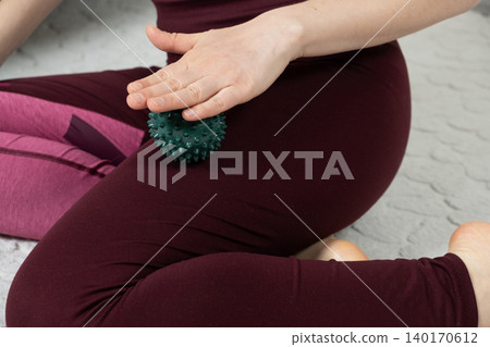 Woman rolling spiky massage ball on thigh for myofascial release close-up Woman rolling spiky massage ball on thigh for myofascial release close-up 140170612