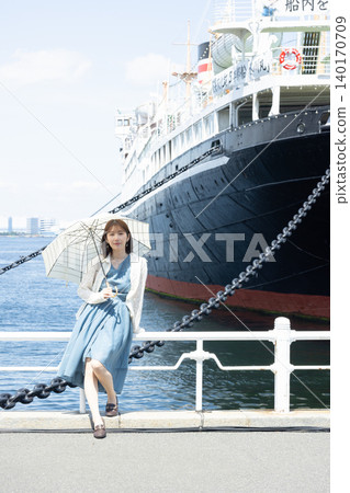 一位神采奕奕的女子撐著陽傘，沿著橫濱海濱漫步。 140170709