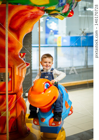 Little boy riding colorful carousel turtle shopping mall amusement area bright decorations Little boy riding colorful carousel turtle shopping mall amusement area bright decorations 140170728