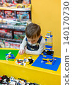 Little boy focused on assembling colorful building bricks at bright yellow table  140170730
