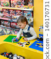Little boy focused on assembling colorful building bricks bright table inside toy store environment 140170731