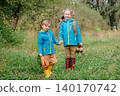 Two children holding hands and carrying fresh carrots and beets while walking  140170742