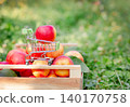 Red apple placed in miniature shopping cart on wooden crate filled  140170758