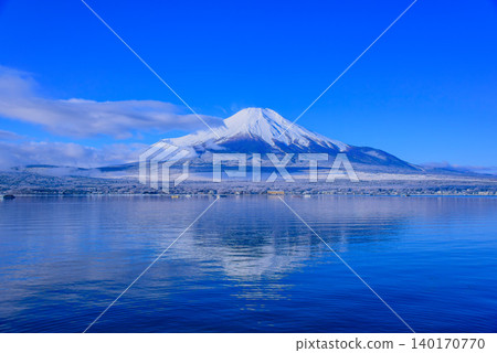 A view of snow-covered Mount Fuji from Yamanakako Waterfront Park in winter, and its reflection shimmering on the water's surface. 140170770