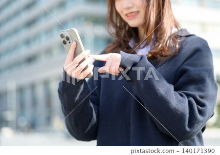 Japanese high school girl looking at her smartphone 140171390