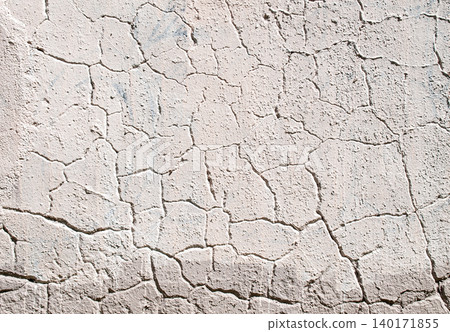 Texture of an old painted plaster wall with deep cracks in bright sunlight. 140171855