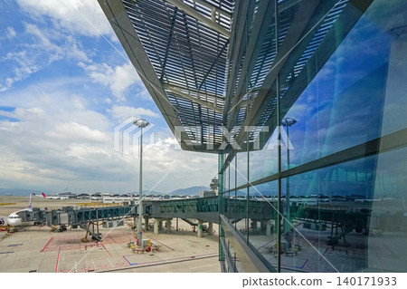 Modern airport terminal with jet bridge and airplane under a cloudy sky 140171933
