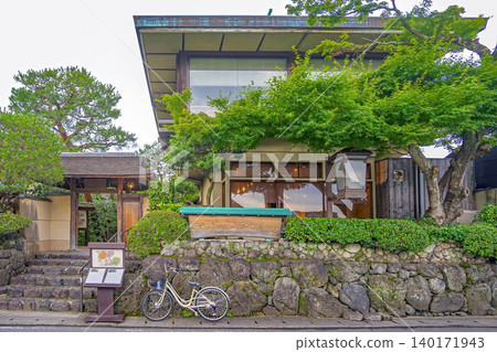 Traditional Japanese architecture with lush greenery and a bicycle parked outside Traditional Japanese architecture with lush greenery and a bicycle parked outside 140171943