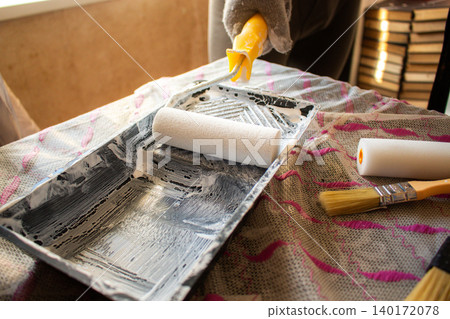 Hand dipping roller into paint tray. Self made home improvement on budget. Cosmetic renovation Hand dipping roller into paint tray. Self made home improvement on budget. Cosmetic renovation 140172078