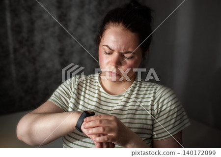 Woman feeling anxiety and stress checking health on smartwatch. Deep fatigue from digital and technologies. Obsession about data tracking Woman feeling anxiety and stress checking health on smartwatch. Deep fatigue from digital and technologies. Obsession about data tracking 140172099