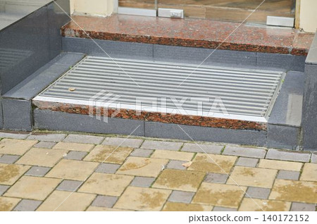 Exterior entrance features elegant stone steps and shiny metal threshold Exterior entrance features elegant stone steps and shiny metal threshold 140172152