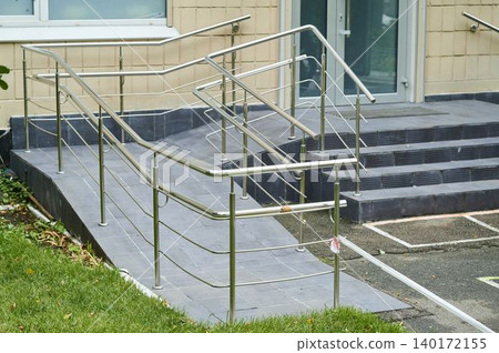 Safe access ramp leading to building entrance with modern handrails in clear daylight 140172155