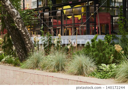 Lively outdoor dining space with greenery and colorful seating near an urban area Lively outdoor dining space with greenery and colorful seating near an urban area 140172244