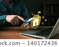 Man using smartphone with smart home security interface. Hologram icons show house shield, cloud, AI, and automation. Concept of home protection, IoT technology, and remote control via internet. 140172436