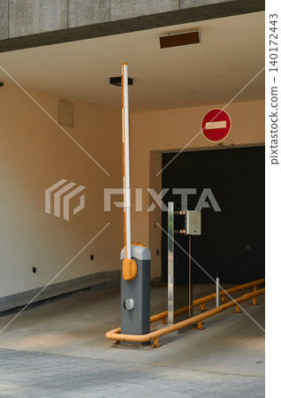 Parking barrier stands at the entrance of a modern garage in a quiet urban area Parking barrier stands at the entrance of a modern garage in a quiet urban area 140172443