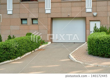 Green shrubs frame a modern building entrance on a sunny afternoon Green shrubs frame a modern building entrance on a sunny afternoon 140172445