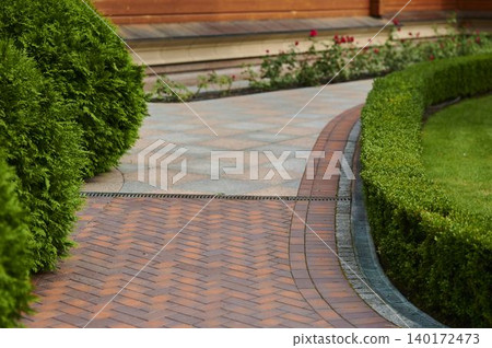 Elegant brick path winding through vibrant greenery in a serene garden setting Elegant brick path winding through vibrant greenery in a serene garden setting 140172473