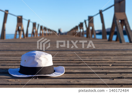 White Summer Hat with Black Ribbon on Beach Pier White Summer Hat with Black Ribbon on Beach Pier 140172484