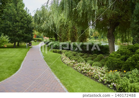 Scenic garden pathway inviting peaceful strolls amidst blooming flowers and lush greenery Scenic garden pathway inviting peaceful strolls amidst blooming flowers and lush greenery 140172488