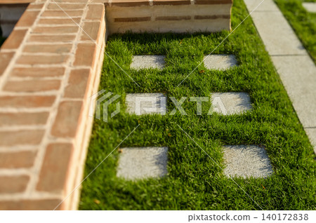 Beautiful garden path with stone tiles and grass Beautiful garden path with stone tiles and grass 140172838