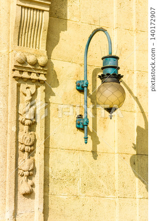 Vintage streetlight gracing an ancient wall 140172907