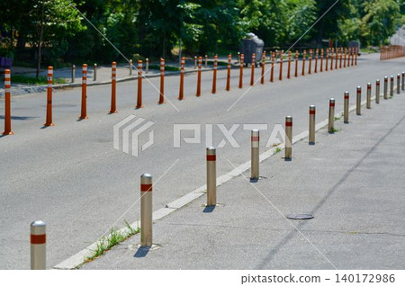 Roadway lined with reflective poles under sunlight 140172986